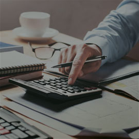 Image of a person using a calculator with a pen in hand