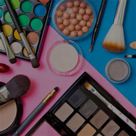 Image of various makeup products laid out on a blue and pink background