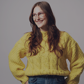 Student in yellow jumper smiling away from camera
